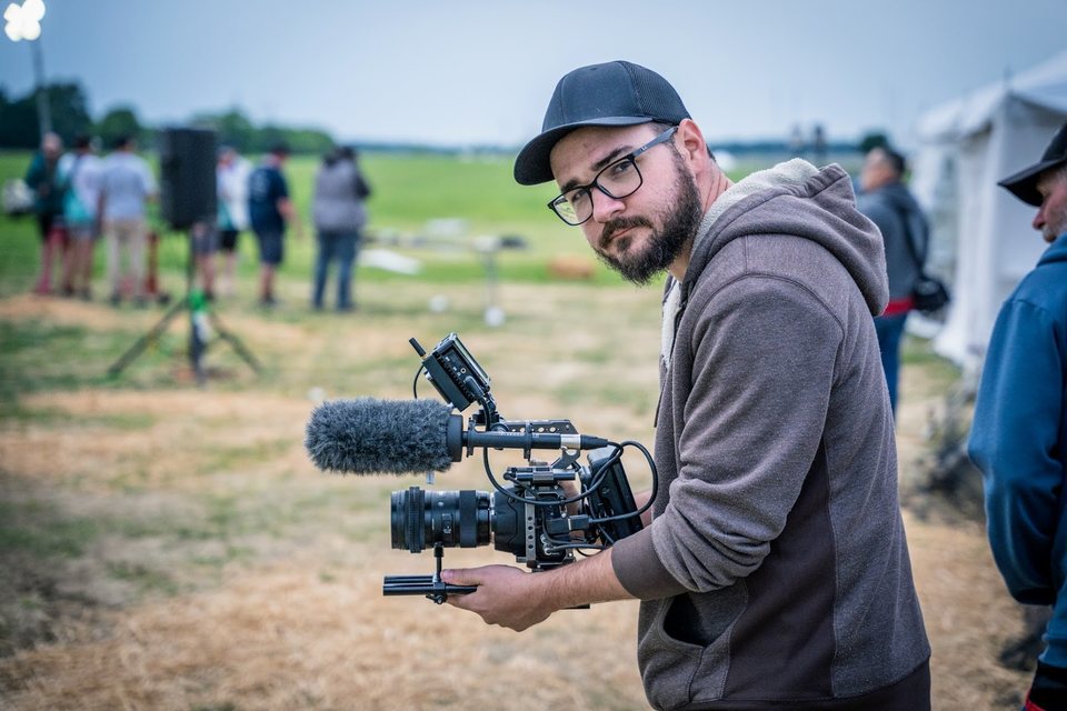 Dillon Carpenter holding a shoulder-rigged cinema camera on location at an outdoor shoot