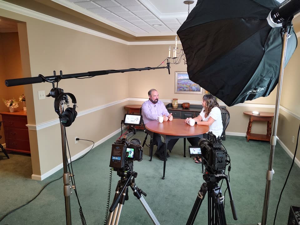 Two-camera interview setup with cinema cameras, softbox lighting, and a boom microphone